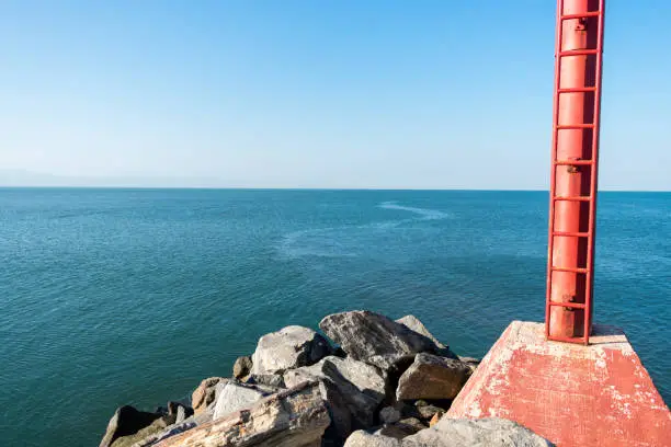 A beautiful horizon scene of a red lighthouse pole with blue beach horizon in Puerto Vallarta