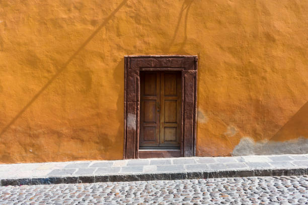 istock Brown worn door with orange wall 953849022