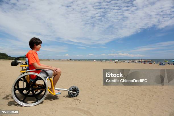 Junge Mit Orange Tshirt Sitzt Auf Den Speziellen Rollstuhl Mit Einer Stockfoto und mehr Bilder von Rollstuhl