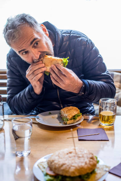 istock Mature Man Eating a Hamburger at Fast Food Restaurant 953858388