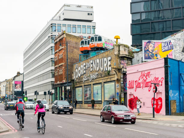 London, UK - Cyclists, cars and pedestrians passing street art in Shoreditch, East London.