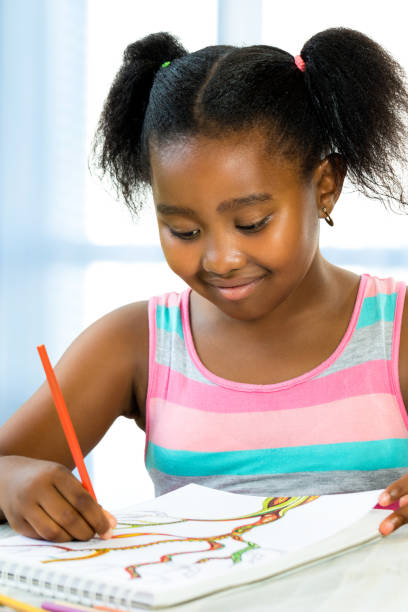 istock Creative little african girl drawing at desk. 953896840