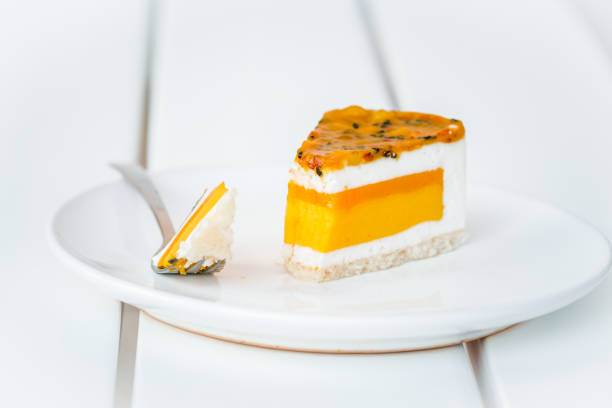 Piece of mango, coconut, passion fruit cake on white wooden table. Minimalism dessert food photography concept