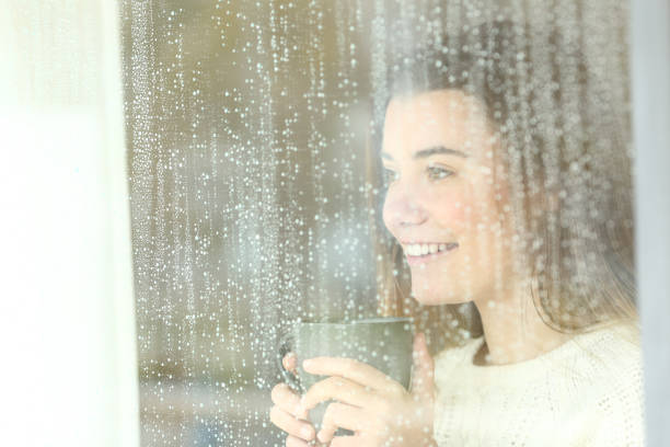 istock Smiley teen looking through a window in a rainy day 953901160