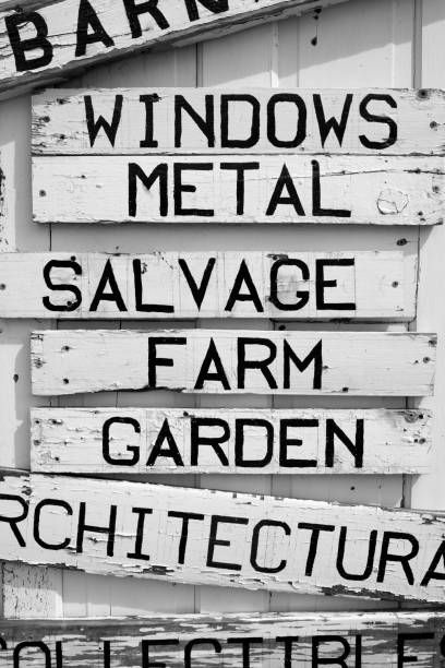 Distressed sales sign outside of antique shop attached to a white door. Words listed on the sign include: windows, metal, salvage, farm, garden, and architecture. cartel de madera con texto - windows, metal, salvamento, granja, jardín y arquitectura muestra ventas madera con texto - coleccionables, diversos compra-venta y comercio cartel de madera con el texto: windows, metal, salvamento, granja, jardín y arquitectura