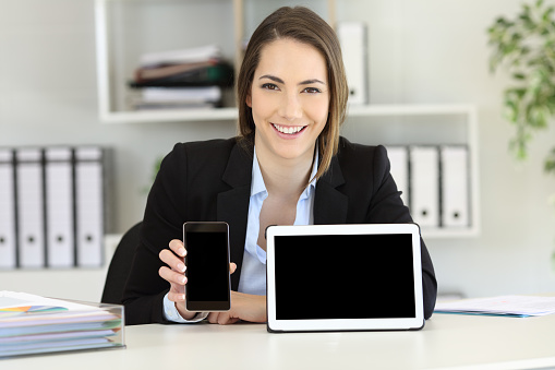 Front view portrait of an office worker showing tablet and smart phone screens