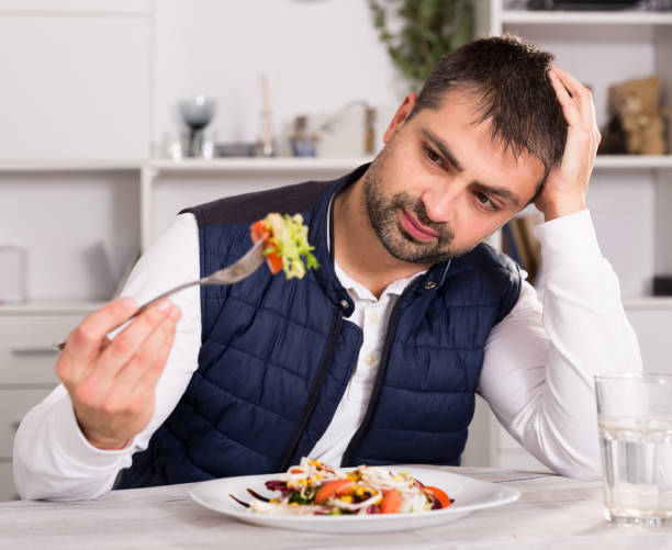 istock Man looking at  vegetable salad before eating  indoors 953905454