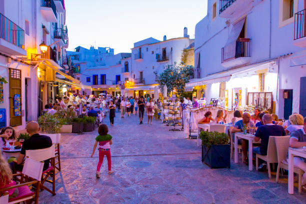 view on crowded street with cafe, bars and restaurants in old town dalt vila,in summer in evening illumination, ibiza, spain - ibiza town imagens e fotografias de stock