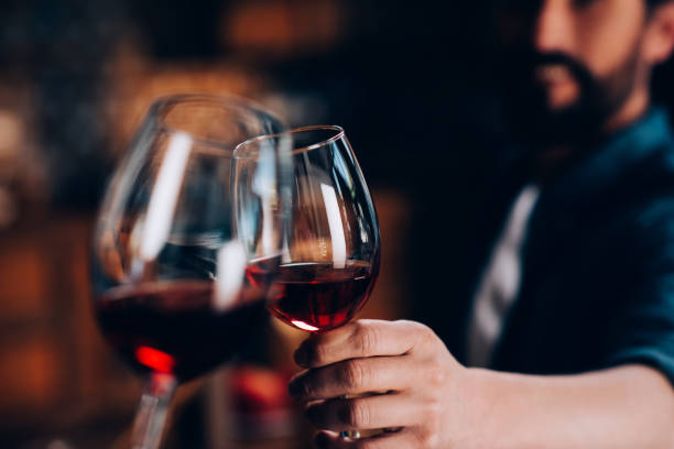 friends drinking red wine close-up partial view of friends clinking glasses of red wine celebratory toast stock pictures, royalty-free photos & images