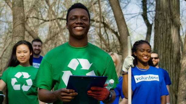 voluntarios diversos alegres en grupo - recycling recycling symbol environmentalist people fotografías e imágenes de stock