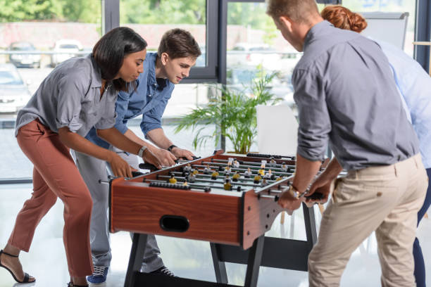 istock Young people playing table football in modern office 953921060