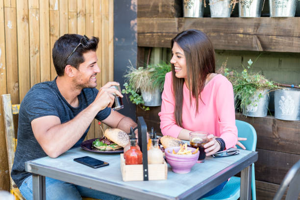 istock Happy young couple seating in a restaurant terrace eating a burger 953924376