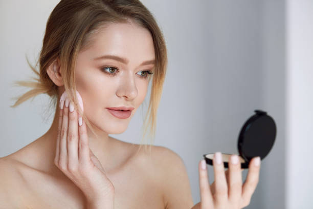 istock Face Make-Up. Female With Mirror Putting Cosmetic Powder 953928676