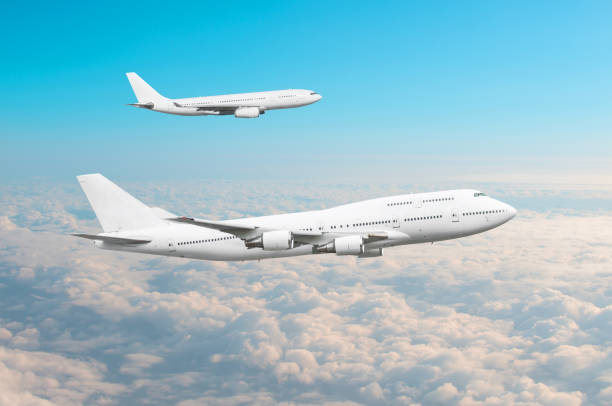istock Two large white passenger airplanes fly parallel to each other in the sky above the clouds. 953928824