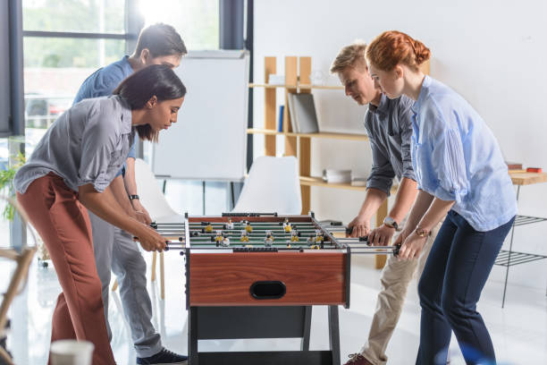 istock Colleagues playing table football in modern office 953936234