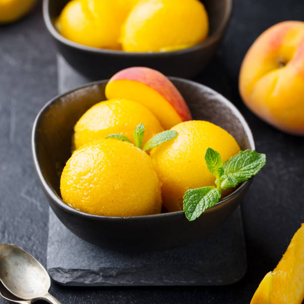 istock Mango, peach ice cream, tropical fruit sorbet in black bowl on stone background 953937074