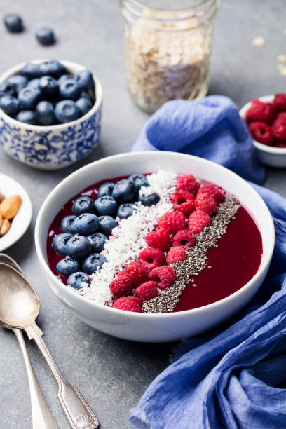 istock Smoothie bowl with fresh raspberry, blueberry, coconut flakes and chia seeds. Grey stone background. 953937958