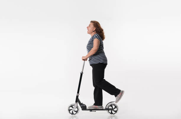 Happy mature women riding scooters over white background