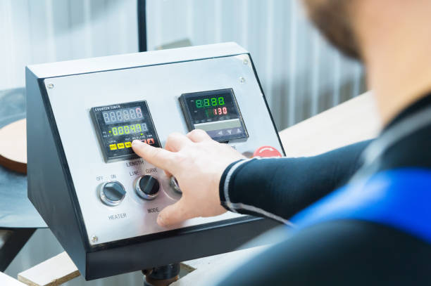 un primer plano del operador el hombre presiona el botón en el panel de control con los dispositivos de control en la producción de muebles. mano del hombre presiona un botón en el panel de instrumentos - machine operator fotografías e imágenes de stock