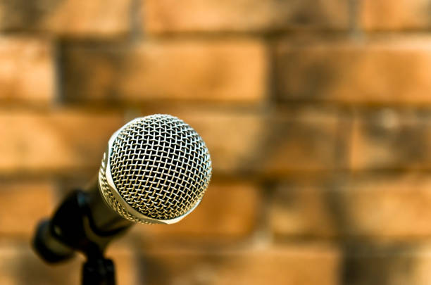 Metallic microphone on the stand beside brick walls stock photo