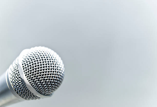 istock Metallic microphone on the stand with grey cement wall 953952570