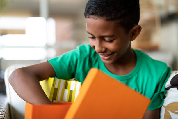 süsser boy öffnen geschenke - kindertag - geburtstagsgeschenk stock-fotos und bilder