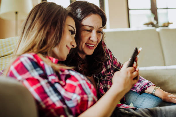 istock Daughter and mother looking at mobile phone 953962346