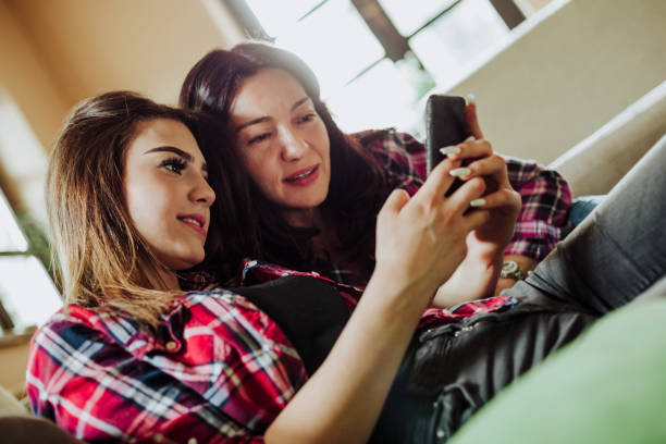 istock Daughter and mother looking at mobile phone 953962618