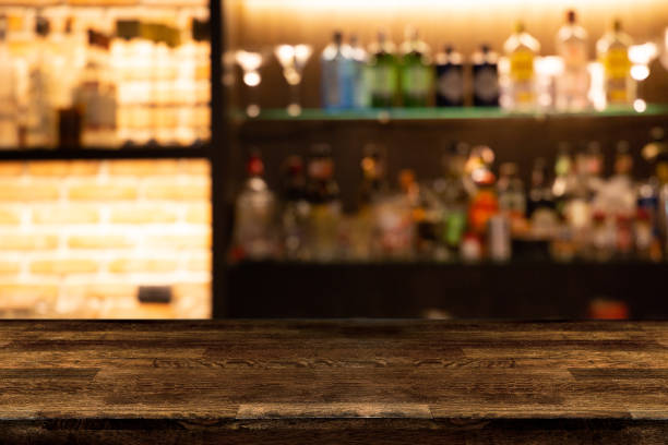 bancone bar vuoto in legno scuro con bottiglie di sfondo sfocate di ristorante. - spirit house foto e immagini stock