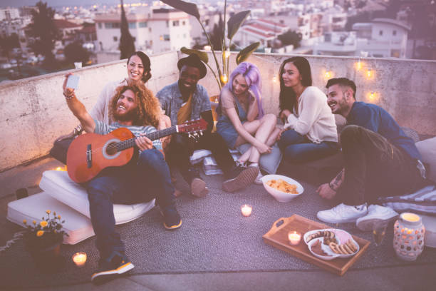 istock Multi-ethnic group of hipster friends taking selfies at rooftop party 953986258
