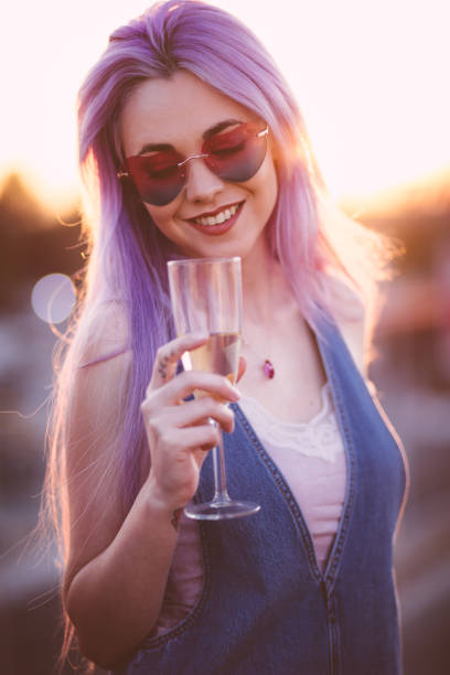 hipster-frau mit lila haaren trinken champagner am sommerfest - flute solo stock-fotos und bilder