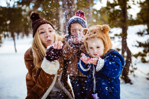 istock Young mother and children having fun playing with snow 953999854