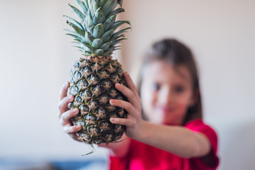 Young girl is showing a pineapple