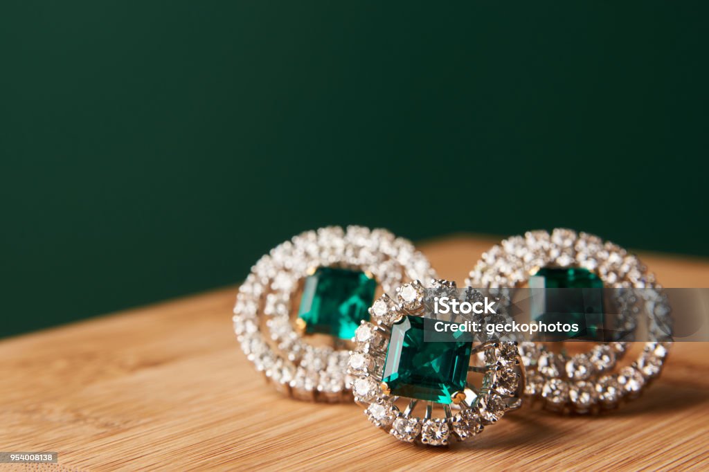 Emerald ring and pair of diamond earrings in gold Emerald ring and pair of diamond earrings in gold, wedding jewelry with luxury gift box , close-up. Selective focus Jewelry Stock Photo