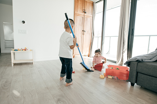 Two kids sweeping and taking off the dirt from the floor.
