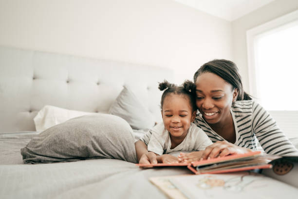 bedtime bonding - family reading african descent book imagens e fotografias de stock