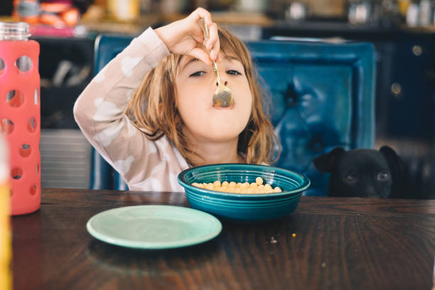 pasto mattutino - little girls small eating breakfast foto e immagini stock