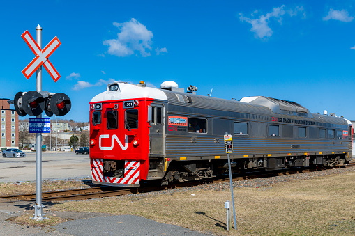 Saint John, New Brunswick, Canada - April 24, 2018: A CN Rain engineering test train travels along the rail tracks taking measurments. Railway crossing sign and lights on the left.