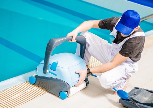 Pool Vacuum Cleaner. Caucasian Swimming Pools Technician with Cleaning Machine.