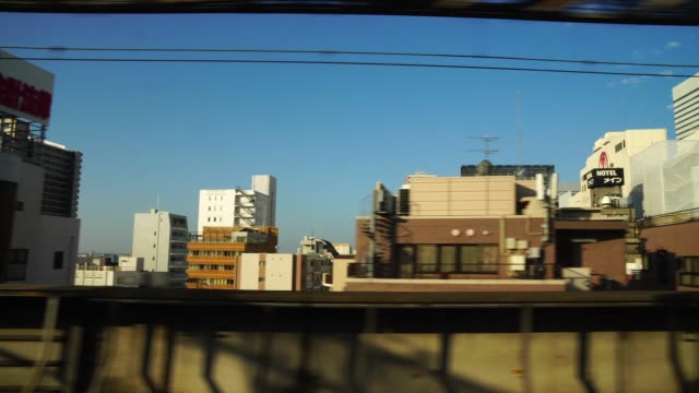 4K footage of Scene from window of the Japanese Train (Shinkansen) which running in tokyo cityscape and pass in the train station with silhouette, Transportation concept