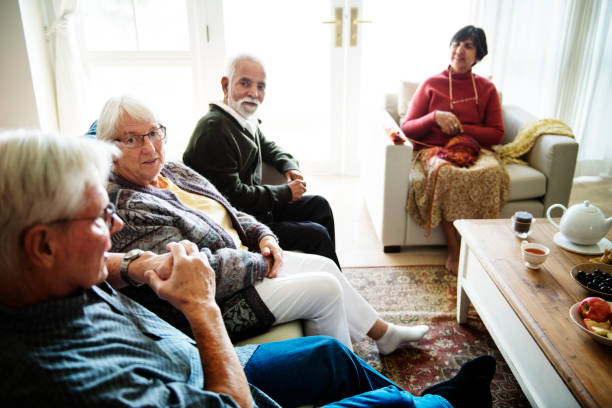 personas mayores sentados juntos en una sala de estar - senior living communitiy fotografías e imágenes de stock