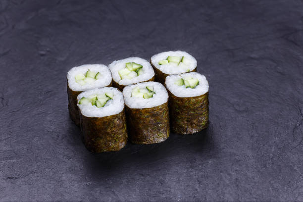 istock Sushi rolls with cucumber, served on black stone slate. Japanese 954061178