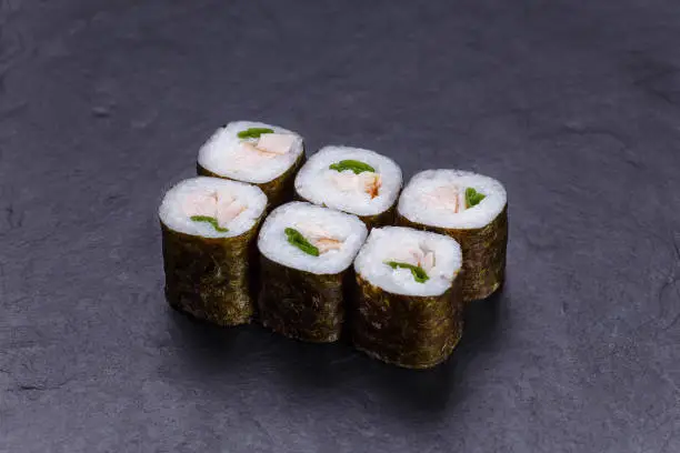 Japanese food, restaurant menu. Sushi rolls with redfish and scallion on black stone table