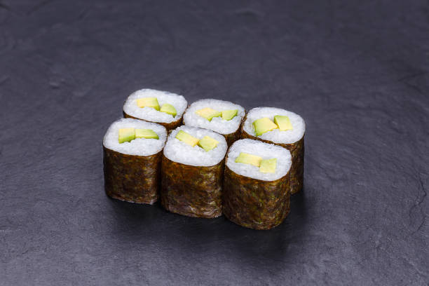 istock Sushi rolls with avocado, served on black stone slate. Japanese 954061548