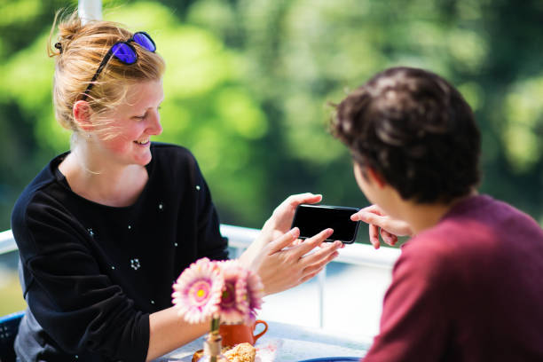 istock Young couple eating breakfast on a patio while looking at a smartphone 954068222