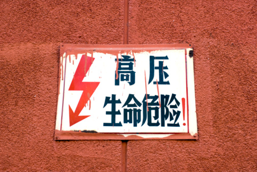 Warning of electrocution risk on orange wall in Beijing, China.