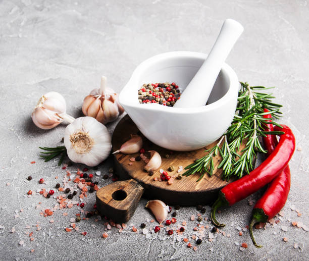Pepper in white mortar and spices on a gray stone background