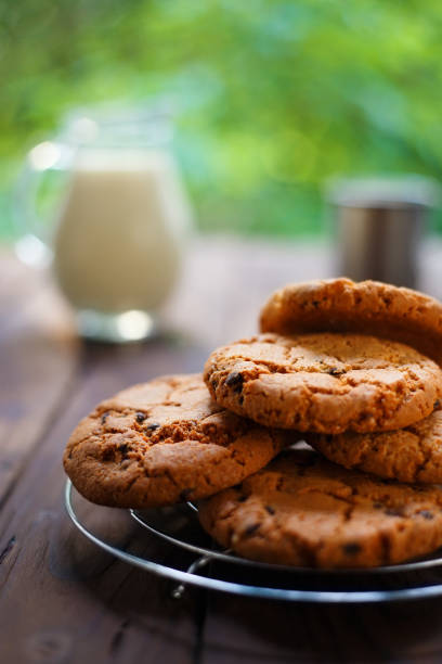 pile de cookies aux pépites de chocolat et verre pot de lait sur w rustique - chocolate chip cookie cookie chocolate stack photos et images de collection