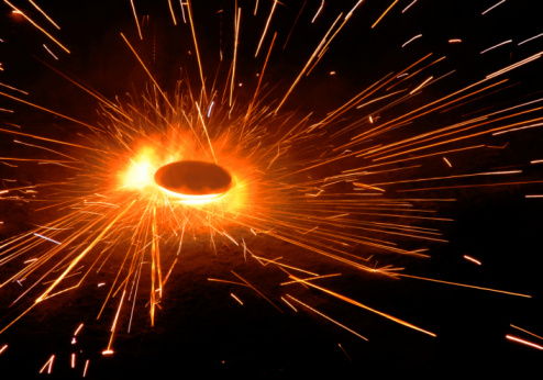Wedding rings on burning bengal light with many sparks on dark background. Marriage proposal for Christmas.