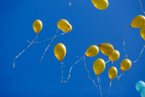 istock Group of floating yellow balloons in the blue sky 954094290